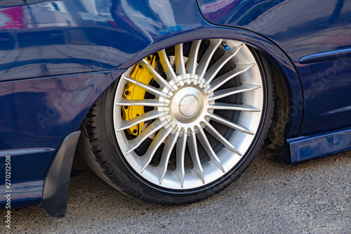 Low rider car tuning. Closeup on the wheel with lowered arch and colored braking system. Car and automibile industry background. photo
