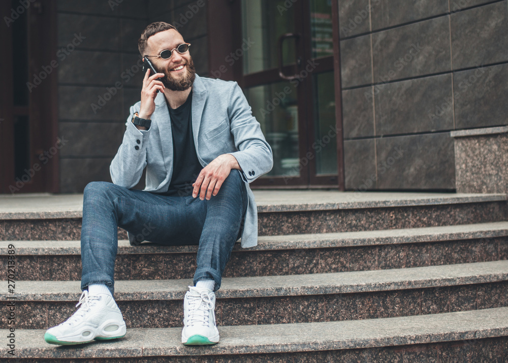 Positive handsome young businessman talking on smartphone while looking away.