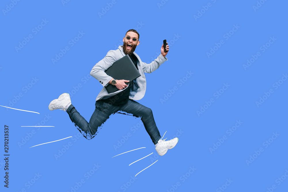 Positive handsome young businessman running in the air along an empty wall. Crazy emotions.
