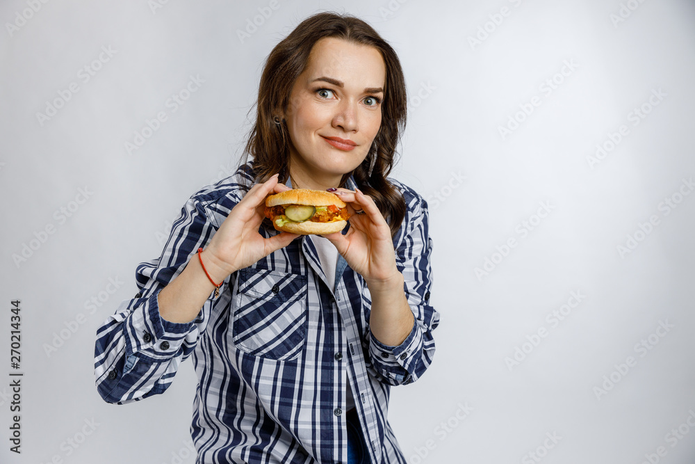 Young beautiful girl holding a Burger on a white background. Fast food, junk food, snack on the go.