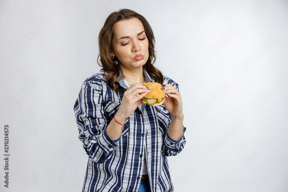 Young beautiful girl holding a Burger on a white background. Fast food, junk food, snack on the go. Young beautiful girl holding a Burger on a white background. Fast food, junk food, snack on the go.