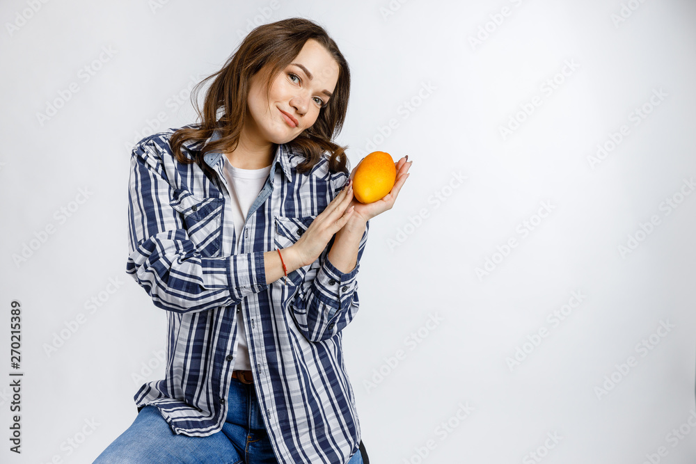 Young beautiful girl in plaid shirt holding mango on white background. Healthy food - vegetables, fruits and berries. Young beautiful girl in plaid shirt holding mango on white background. Healthy food - vegetables, fruits and berries.