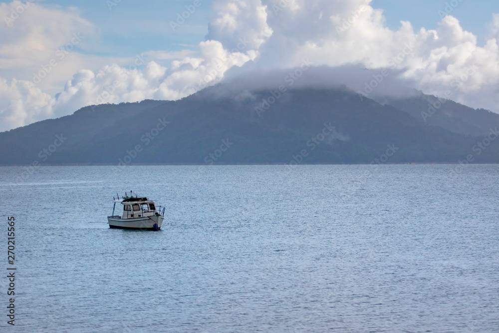 speed boat floating over blue sea water against cloudy sky over island speed boat floating over blue sea water against cloudy sky over island