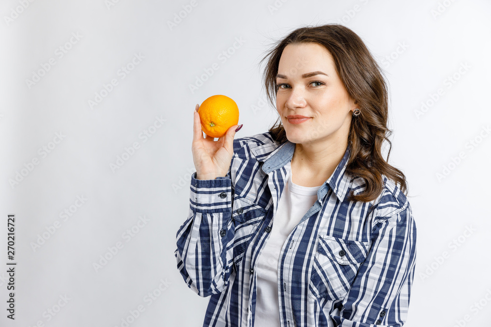 Young beautiful girl in plaid shirt holding orange on white background. Healthy food - vegetables, fruits and berries. Young beautiful girl in plaid shirt holding orange on white background. Healthy food - vegetables, fruits and berries.