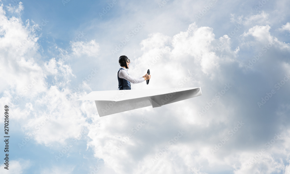 Businessman in aviator hat sitting in paper plane Businessman in aviator hat sitting in paper plane