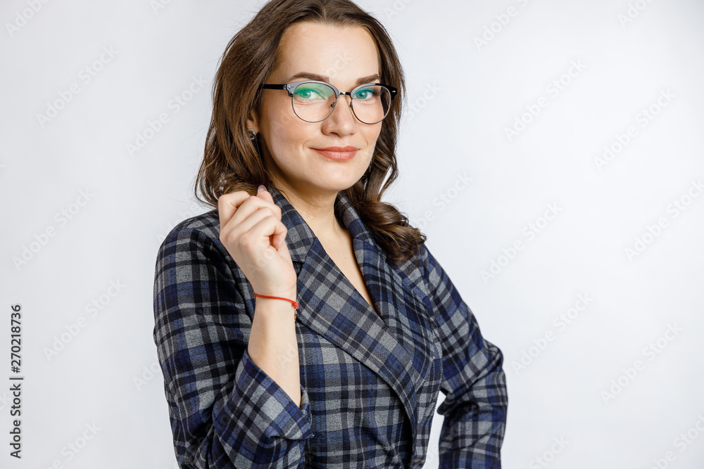 Young beautiful girl in a strict plaid suit posing on a white background. Emotions and feelings at work and office.