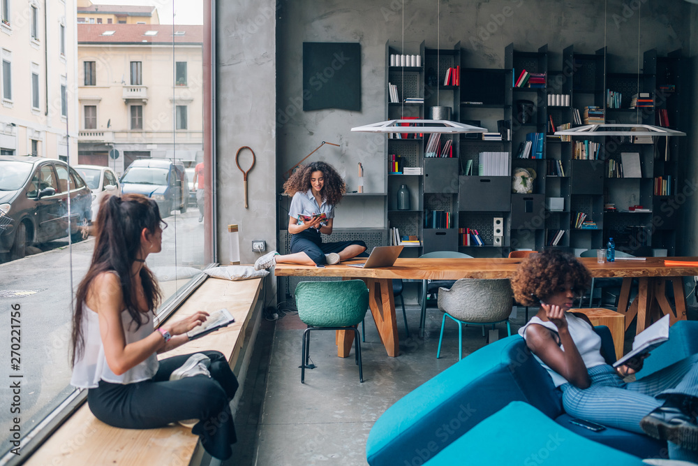 three multiracial young businesswomen working in modern coworking office