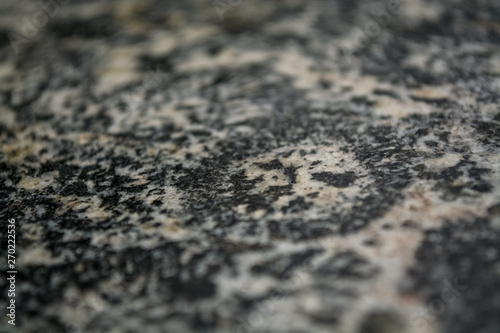 Background or texture from a gray stone with round spots and stains. Natural material. Glossy surface.