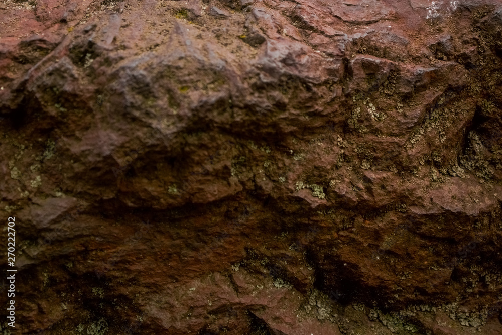 Background or texture from a red stone with cracks and the broken-away parties with an impregnation a moss. Natural material. Background or texture from a red stone with cracks and the broken-away parties with an impregnation a moss. Natural material.