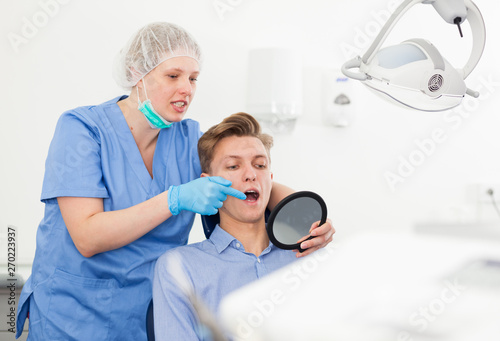 Patient showing dentist the problem in the mirror at the dental clinic