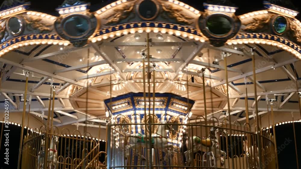 Illuminated merry go round in park. Brightly illuminated roundabout spinning in wonderful amusement park at night.