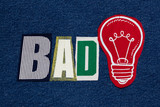 BAD Idea lightbulb and text word collage, colorful fabric on blue denim, business concept, horizontal aspect