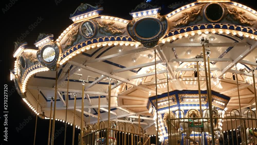 Illuminated merry go round in park. Brightly illuminated roundabout spinning in wonderful amusement park at night.