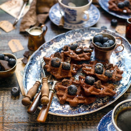 Quadro su tela Homemade yummy chocolate waffles on vintage plates with blue ornament stands on