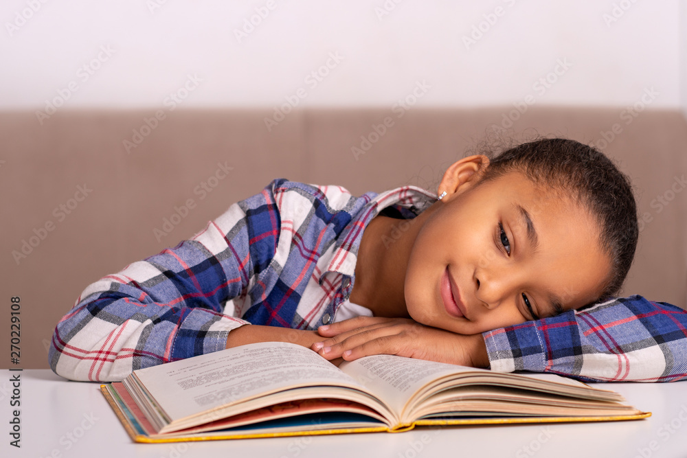 The schoolgirl sits at the table at home and does his homework. The schoolgirl sits at the table at home and does his homework.