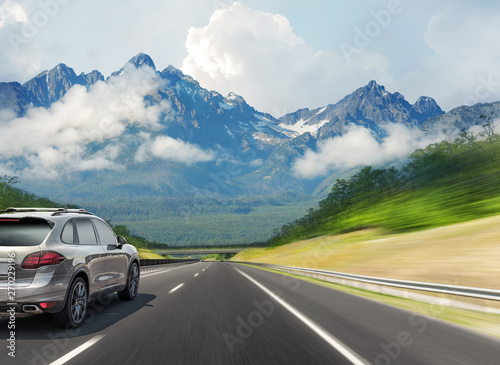 Car drives fast on the highway against the backdrop of a mountain range. © Denis Rozhnovsky