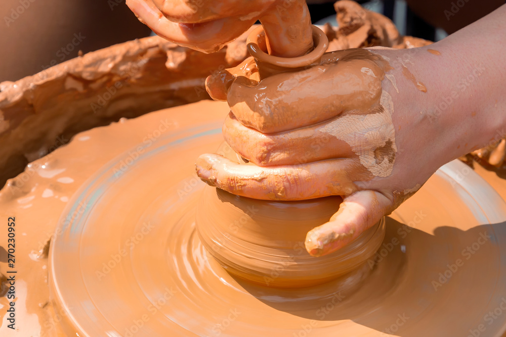 Street potter makes a vase of clay on a potter's wheel. Close-up