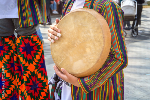 Street musician plays a traditional Asian musical instrument - doira. Close-up photo