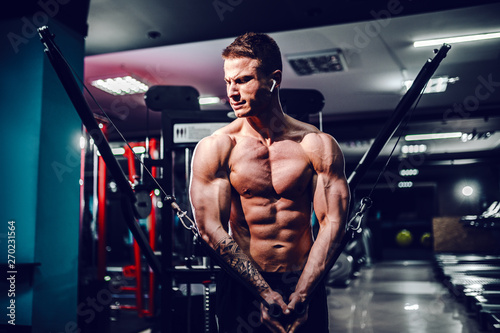 Muscular body builder working out at the gym doing chest fly exercises on the wire cable machine. photo