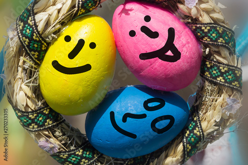 three Egg faces are around some easter eggs.