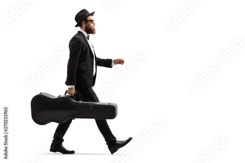 Male musician walking with a guitar case