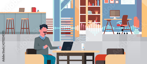 man sitting at workplace with laptop using intelligent smart speaker with voice recognition artificial intelligence assistance concept modern workspace office interior flat horizontal portrait