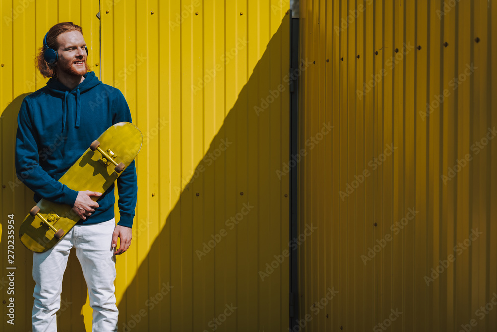 Smiling skater man on yellow fence view Smiling skater man on yellow fence view