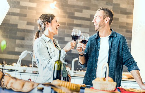 Canvas Print Young couple in love drinking red wine at house kitchen - Happy millenial people