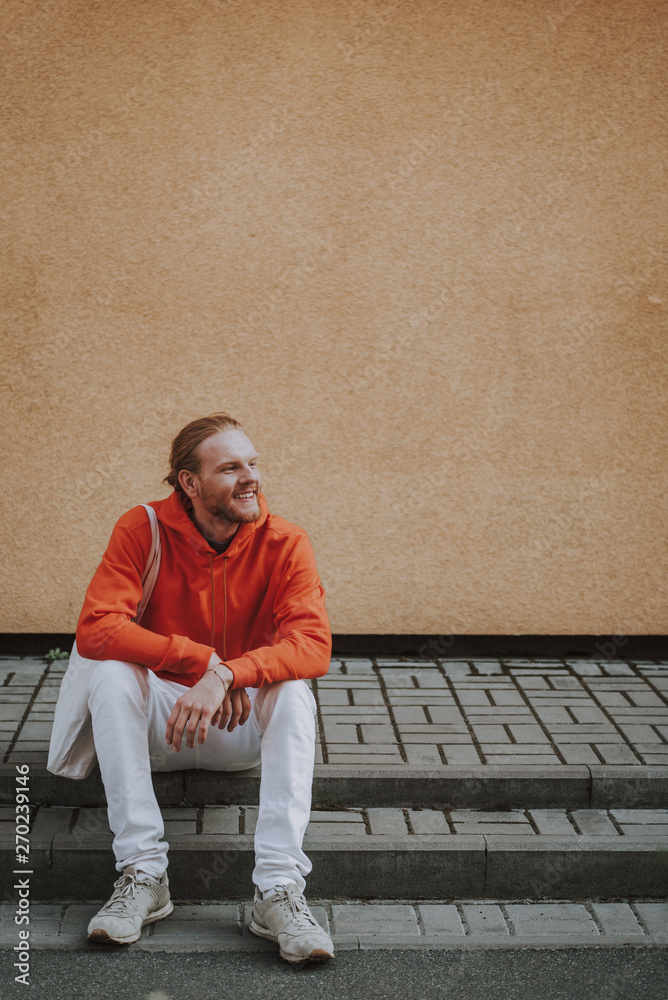 Happy smiling hipster man sitting on stairs Happy smiling hipster man sitting on stairs