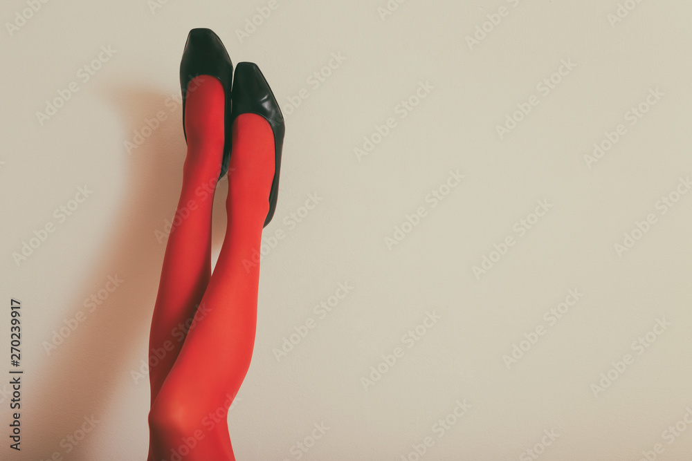 Beautiful legs of a woman in red tights and high heels up in front of wall.Toned photo Beautiful legs of a woman in red tights and high heels up in front of wall.Toned photo