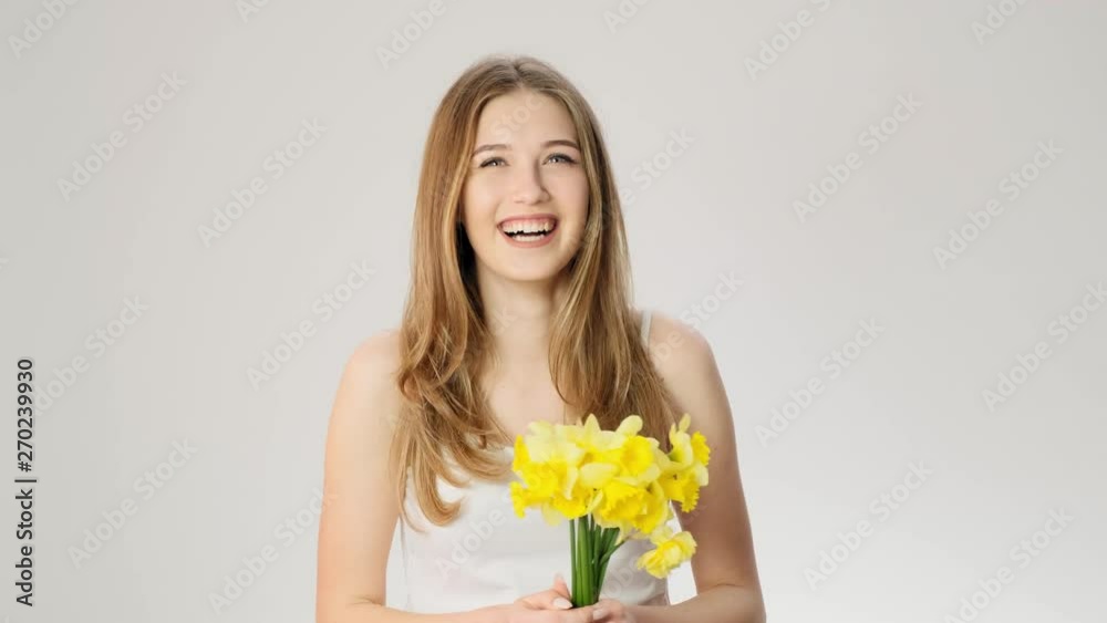 Happy shy young woman holds yellow flowers slow motion