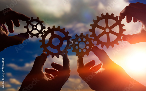 gears in the hands of people against the sky. mechanism, work in the company