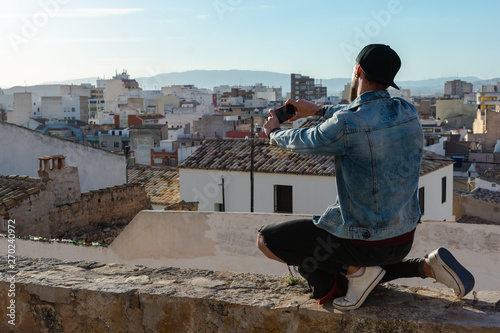 Young man takes a picture with the city in the background