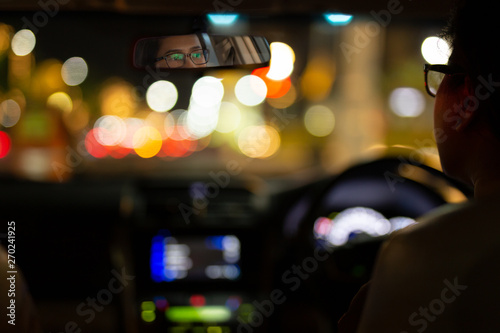 Woman driving car with bokeh lights from traffic jam at night time.