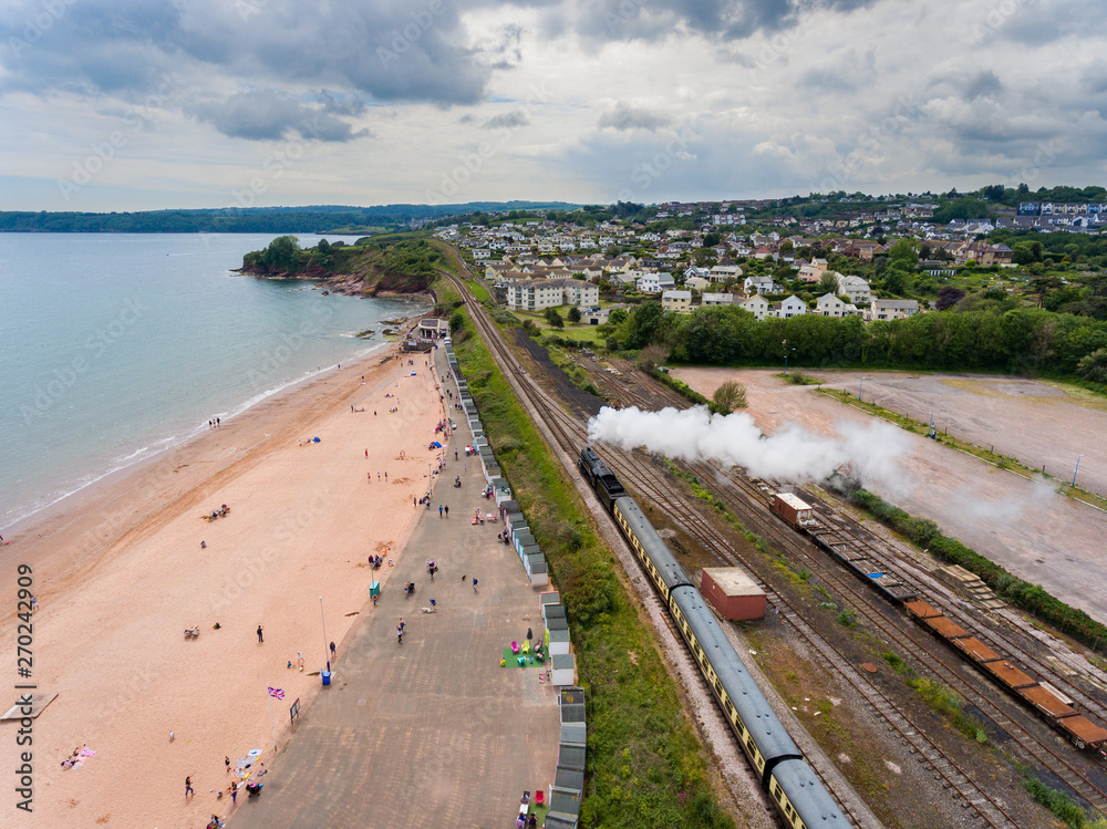 Aerial View of a Steam Passenger Train Puffing Smoke by Devon coastline on a summer Day