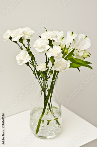 White flowers in glass vase on a shelf