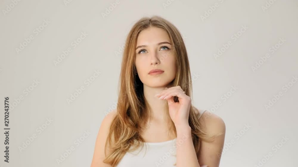 Young upset thoughtful woman smiles on the white background slow motion Young upset thoughtful woman smiles on the white background slow motion