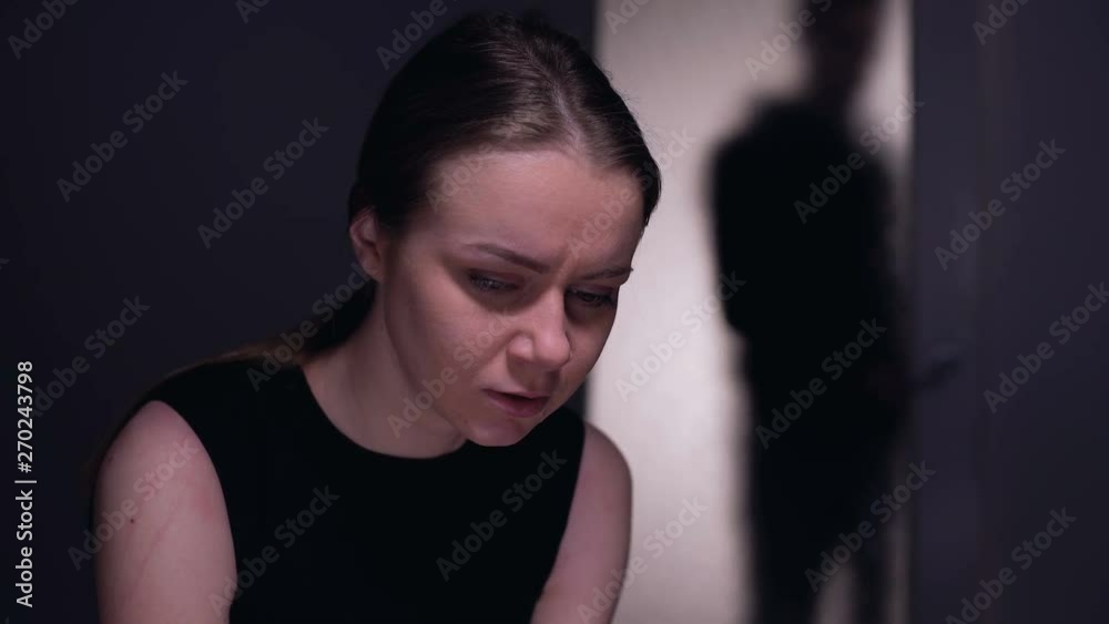 Scared kidnapping victim looking at male silhouette entering room, mistreatment Scared kidnapping victim looking at male silhouette entering room, mistreatment