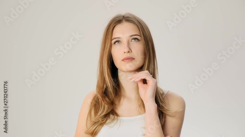 Young upset thoughtful woman smiles on the white background slow motion