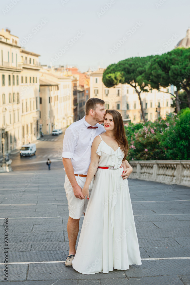 young beautiful couple in white clothes walks in Rome in Italy at sunset young beautiful couple in white clothes walks in Rome in Italy at sunset