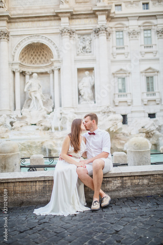 young beautiful couple in white clothes stands near Trevi Fountain in Rome in Italy