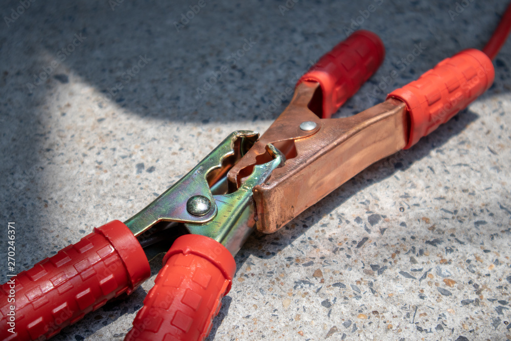 Jumper cables connect to another jumper cables for longer cables on cement ground. Jumper cables connect to another jumper cables for longer cables on cement ground.