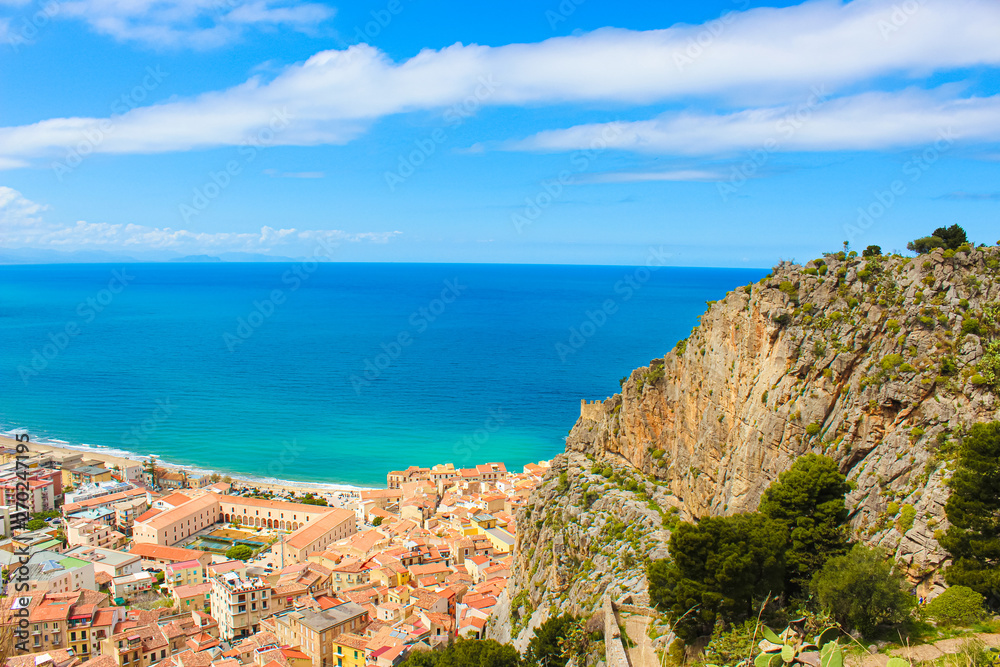 Beautiful seascape surrounding Italian coastal city Cefalu. The beautiful city on Tyrrhenian coast in Sicily is popular summer vacation destination. Taken from above with rocks adjacent to the bay