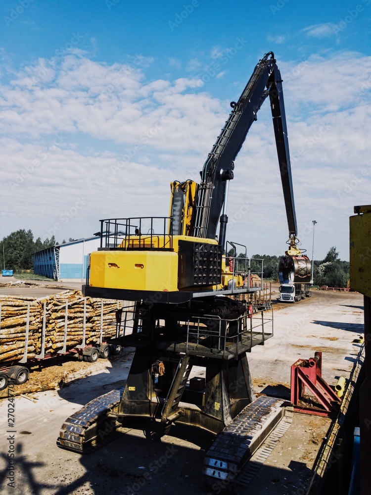 Yellow crane unloading logs in the port