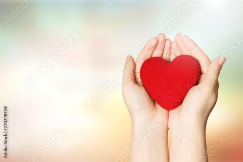Hands of young woman holding red heart
