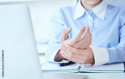 Young woman holding her wrist close-up . Pain from using computer. Office syndrome hand pain by occupational disease.