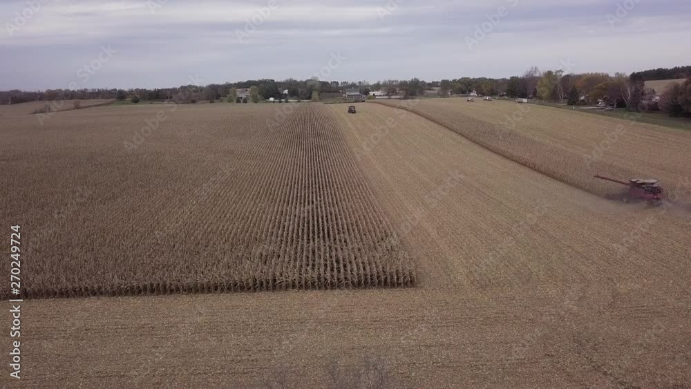 Aerial pullback over a golden corn field being cut by a combine harvester Aerial pullback over a golden corn field being cut by a combine harvester