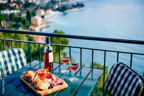 Fototapeta Naklejka Na Ścianę i Meble -  Two glasses of wine and italian snacks  with amazing view at sunset in Italy.