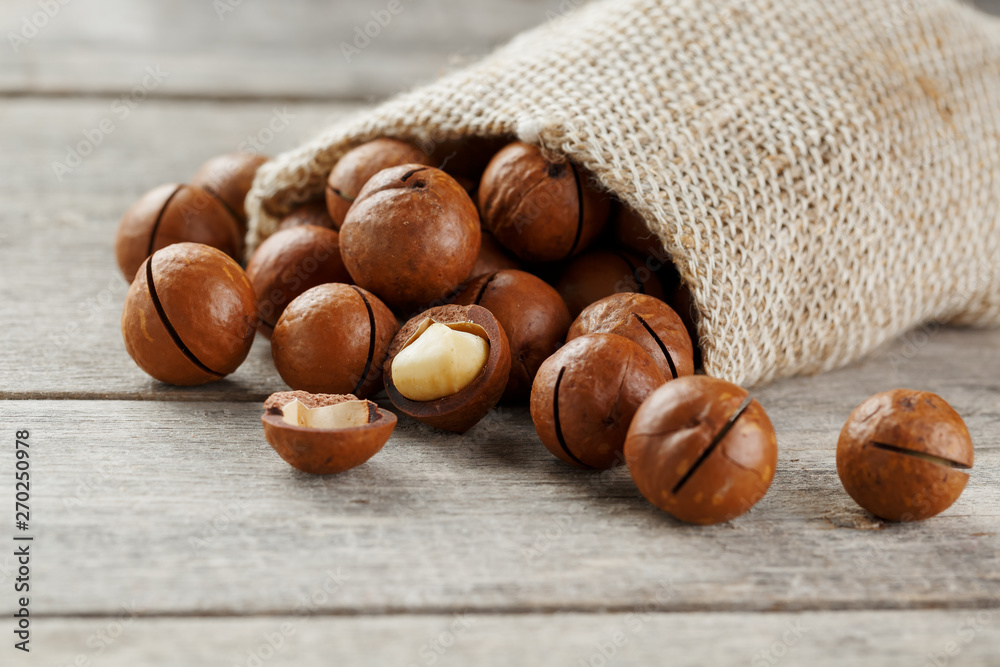 Macadamia nut on a wooden table in a bag, closeup, top view Macadamia nut on a wooden table in a bag, closeup, top view
