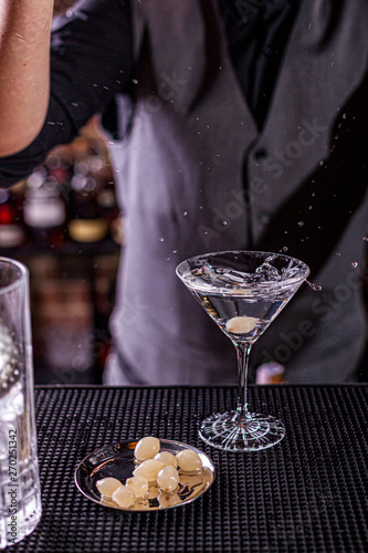 vodka martini isolated on a black background with an olive splashing and air bubbles